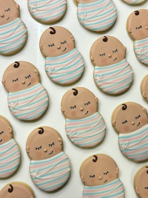 Sleeping-baby swaddle cookies piped in pastel pink and blue stripes