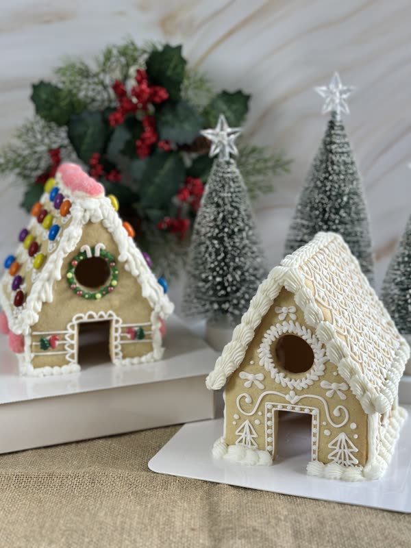 Two cookie houses side by side — a candy-decorated build and a white piped one