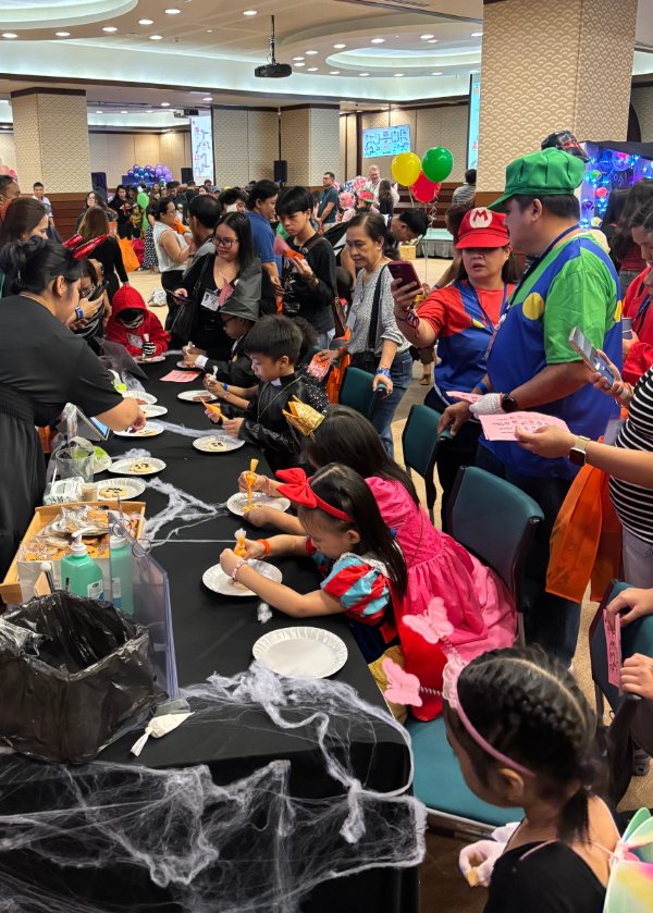 A Halloween fair in full swing — costumed kids piping cookies at our booth table